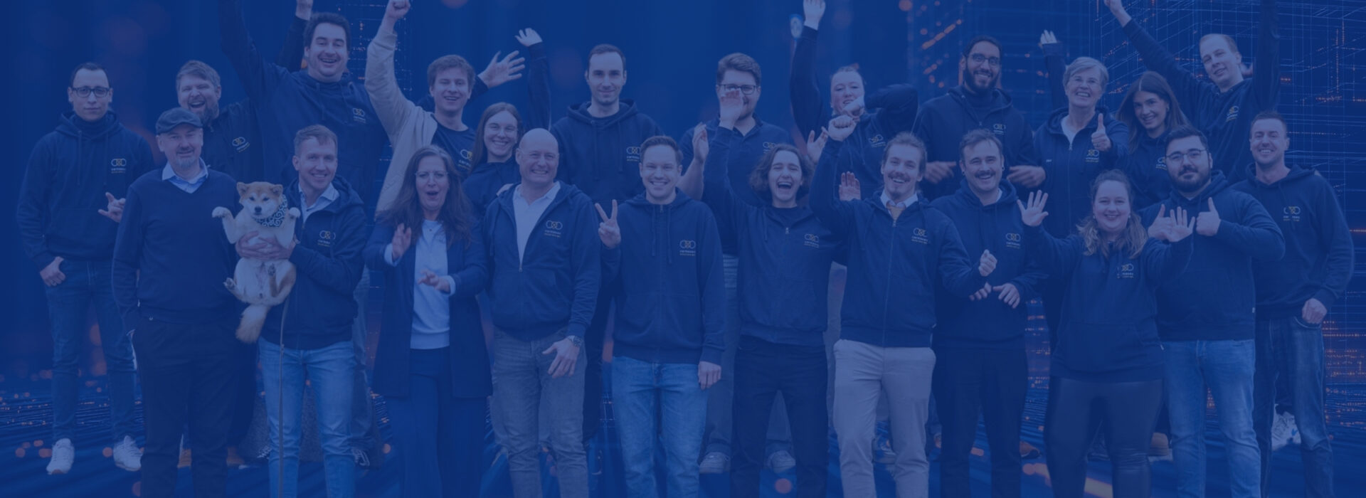 Gruppenfoto des carmasec-Teams in dunkelblauen Firmen-Hoodies, freudig winkend und posierend