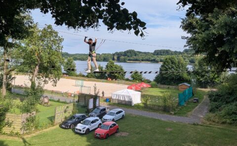 carmasec-Mitarbeiter beim Teambuilding auf einem Hochseilparcours vor einem See