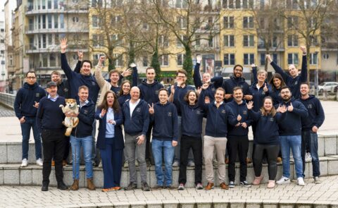 Das carmasec-Team feiert gemeinsam für ein Gruppenfoto im Freien, gekleidet in dunkelblaue Firmen-Hoodies