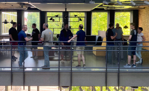 Gruppenfoto von Teilnehmenden des carmasec Cyber Circle Meetups im Gespräch auf einer Galerie in modernem Loft-Ambiente