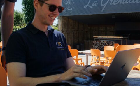 Pascal Waffenschmidt, Senior Security Consultant bei der carmasec, arbeitet lächelnd an einem Laptop im Außenbereich von La Grémille