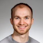 Profilbild Consultant Chris Pauels. Lächelnde Person mit grauen Poloshirt.